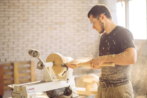 O homem que trabalha no torno de madeira pequeno, um pedaço de madeira do carves do artesão — Fotografia de Stock
