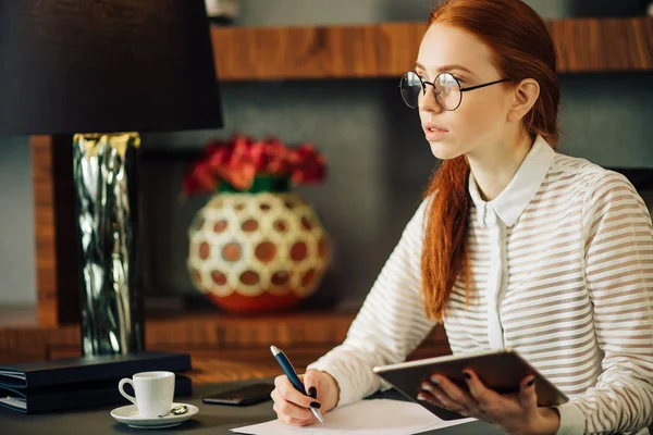 Mujer escribiendo en papel con tableta digital en la sala de oficina — Foto de Stock