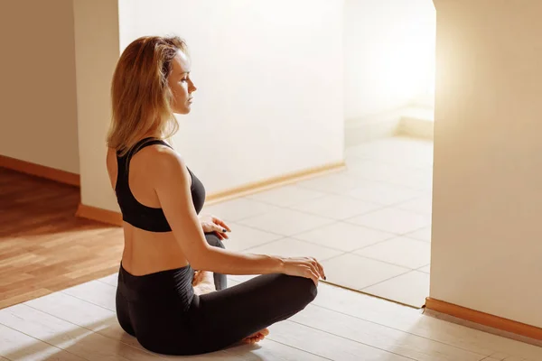 Hermosa mujer sentada en pose de loto y meditando en estudio de yoga — Foto de Stock