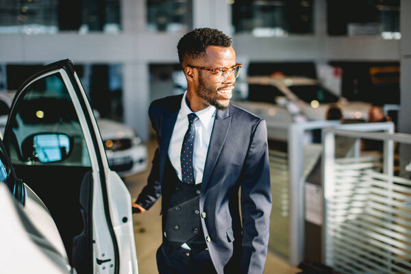Африканский американский водитель открывает дверь своей новой машины
