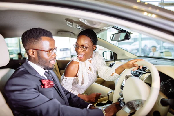 Belo casal africano está escolhendo carro novo na concessionária . — Fotografia de Stock