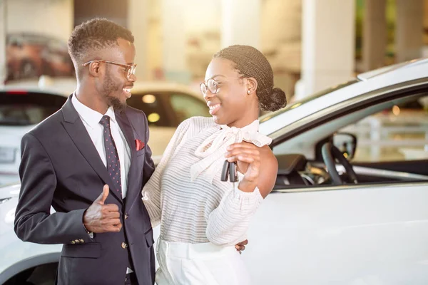 A visitar a concessionária de carros. casal segurando a chave de seu carro novo, olhando para a câmera — Fotografia de Stock