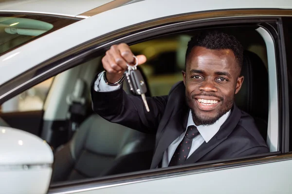 Jovem empresário africano sentado em um carro mostrando chave do carro — Fotografia de Stock