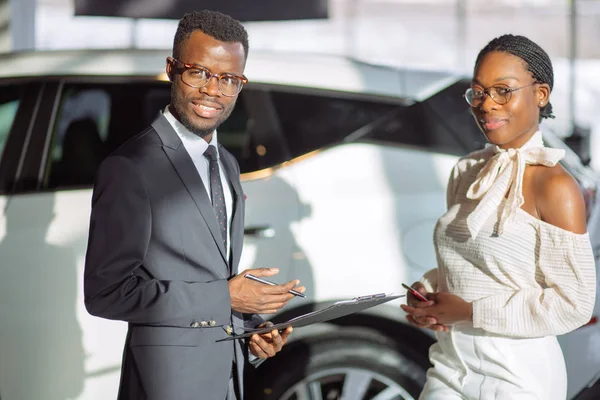 Car dealer showing vehicle to black woman — Stock Photo, Image