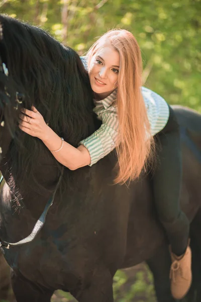 Young rider girl with long hair lying on horse neck — Stock Photo, Image