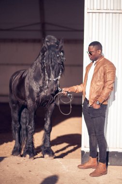 Afrika adam hangarda siyah at yakınındaki güneş gözlüğü takıyor