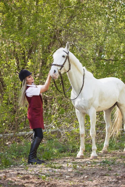Красивая брюнетка с длинными волосами позирует с красной лошадью в лесу — стоковое фото
