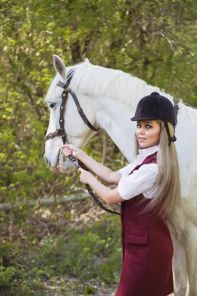 Hermosa chica morena con el pelo largo posando con un caballo rojo en el bosque —  Fotos de Stock