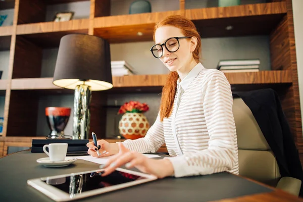 Vöröshajú mosolygó fiatal nő manager segítségével modern digitális tábla irodában — Stock Fotó