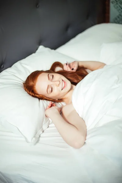 Sovande ung kvinna ligger i sängen med slutna ögon. ovanifrån — Stockfoto