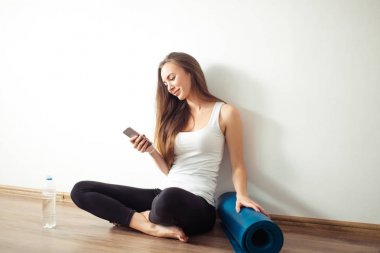 Yoga yaparken ve cep telefonuyla katta oturan kadın