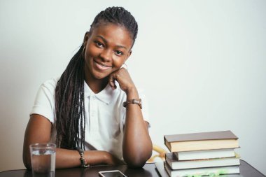 evde kitap ile masada oturan Afrikalı genç bayan