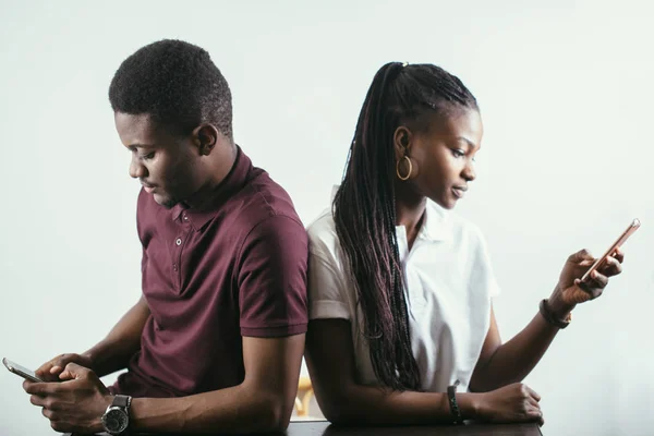 Pareja africana sosteniendo teléfonos móviles en una mano — Foto de Stock