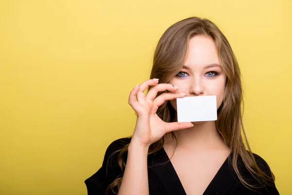 Jeune femme tenant une carte bancaire isolée sur fond jaune — Photo