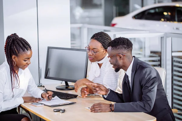 Felice coppia africana con rivenditore acquisto di auto in salone o salone di auto — Foto Stock