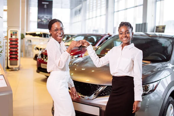 two african american woman near car with keys in hand - concept of buying car