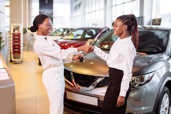 顾客在汽车经销处买车。女人和男人握手 — 图库照片