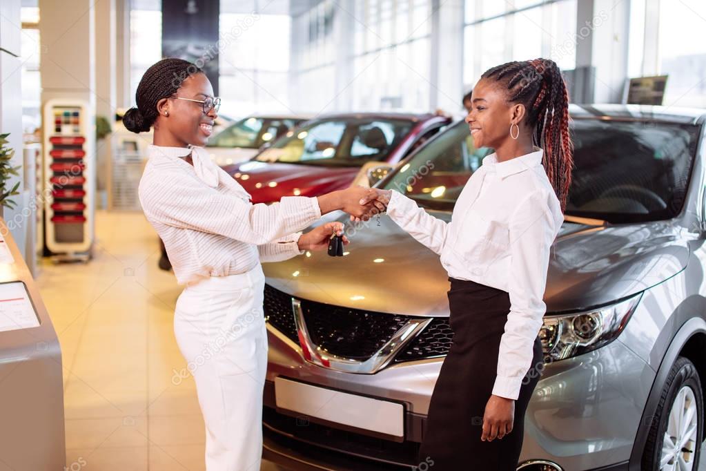 Customer buying a vehicle at car dealership. woman and man handshaking