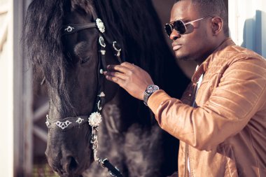 Afrika adam hangarda siyah at yakınındaki güneş gözlüğü takıyor