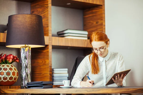 Donna che scrive su carta con tablet digitale in ufficio — Foto Stock