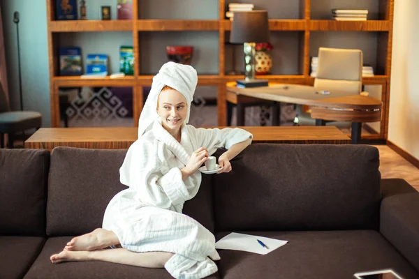 Ung kvinna i badrock dricka kaffe och läsa på digitala tablett — Stockfoto