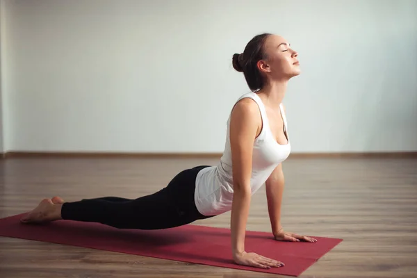 Frau praktiziert Yoga im Haus. schöne Mädchen Praxis Cobra Asana in der Klasse — Stockfoto