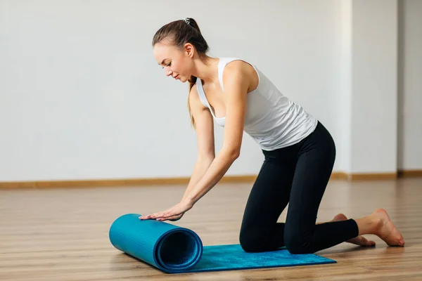 Mujer practicando yoga, preparándose para el ejercicio, desenrollando o rodando estera de yoga —  Fotos de Stock