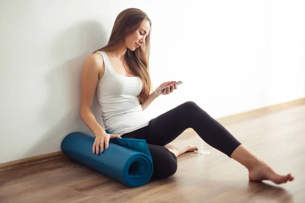 woman doing yoga and using cell phone sitting on the floor