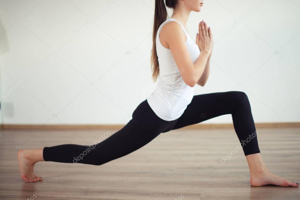 woman practicing yoga, standing in Warrior one exercise, Virabhadrasana