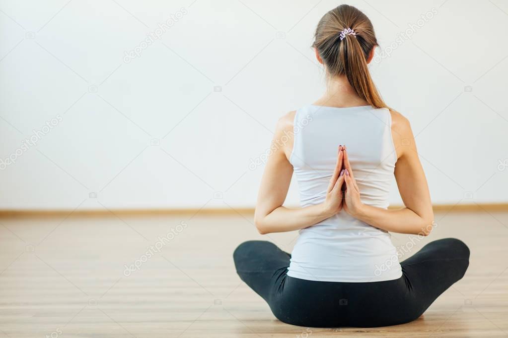 woman practicing yoga with namaste behind back