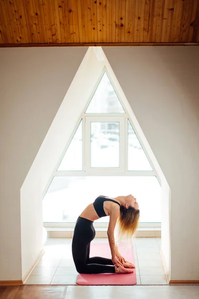 Femme dans le dos posture de yoga inversée, vue latérale, habillée en noir — Photo