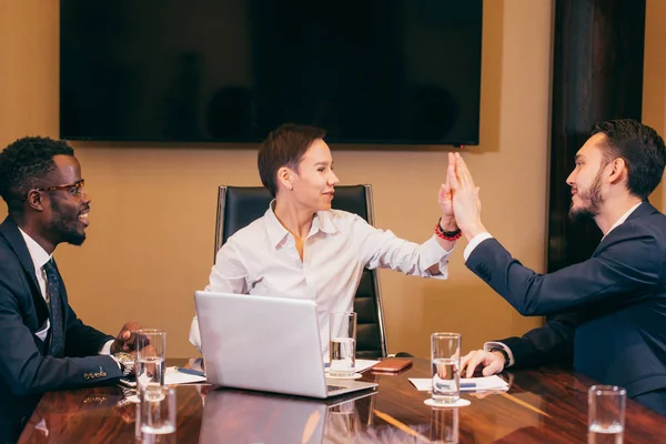 business team giving high fives gesture as they laugh and cheer their success