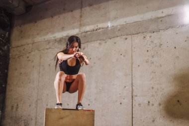 kadının bir kutu atlama egzersiz yapması uygun. Kaslı kadın spor salonunda bir kutu ağız kavgası yapıyor