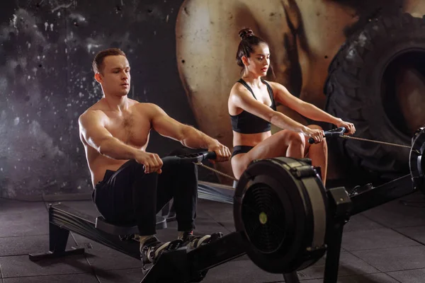 Couple doing exercises with rowing machine — Stock Photo, Image