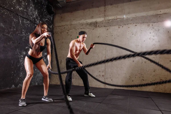 Woman and man couple training together doing battling rope workout — Stock Photo, Image