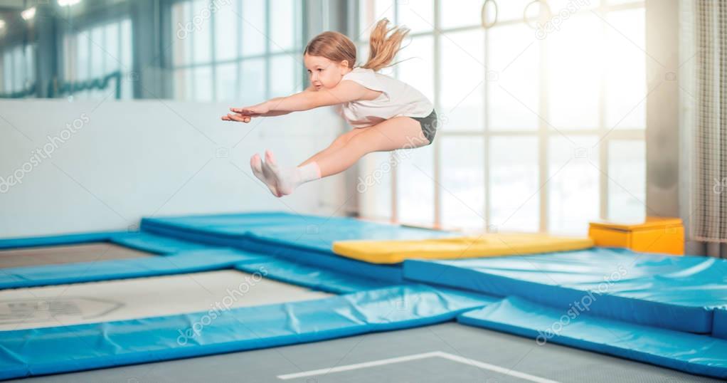 Girl jumping high in striped tights on trampoline.