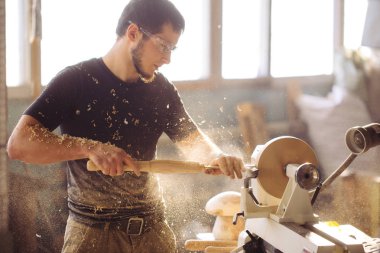 man working at small wood lathe, an artisan carves piece of wood clipart