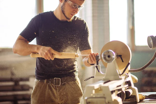 Человек, работающий на небольшом токарном станке, ремесленник вырезает кусок дерева — стоковое фото