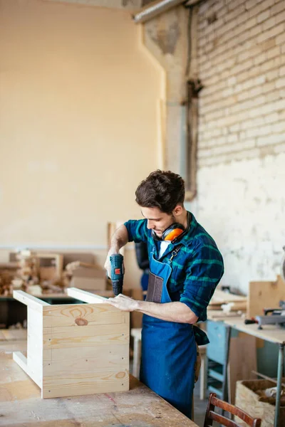 Carpenter drills a hole with an electrical drill — Stock Photo, Image