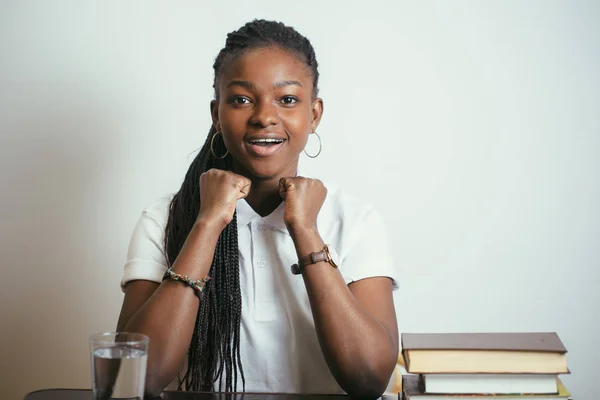 Afrikanska ung kvinna sitter vid bord med böcker hemma — Stockfoto
