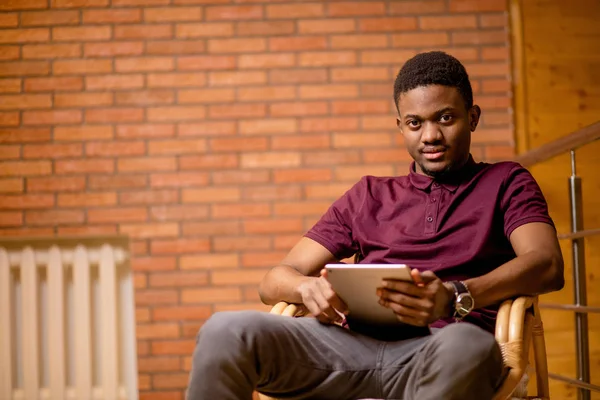 Afrikaanse man met behulp van Tablet PC voor video gesprek terwijl u ontspant op fauteuil — Stockfoto