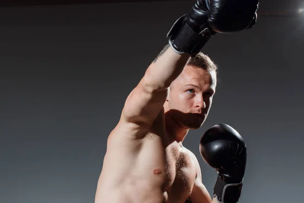 Sporty man during boxing exercise making direct hit