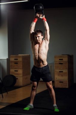 kettleball yandan, koyu arka planı olan adam