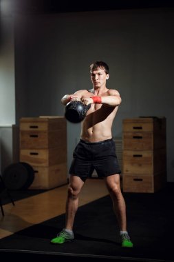 Güzel atlet kettlebell yapıyor salıncaklar. Arkadan görüntüleyin. Atlet çıplak göğüslü