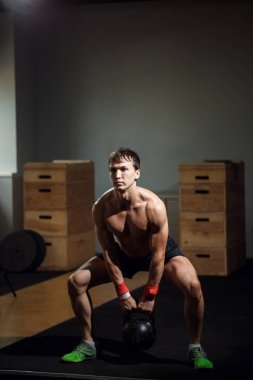 Güzel atlet kettlebell yapıyor salıncaklar. Arkadan görüntüleyin. Atlet çıplak göğüslü