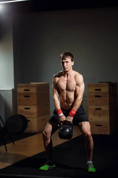 Treino cruzado intensivo. homem de sportswear trabalhando com kettle bell no ginásio — Fotografia de Stock