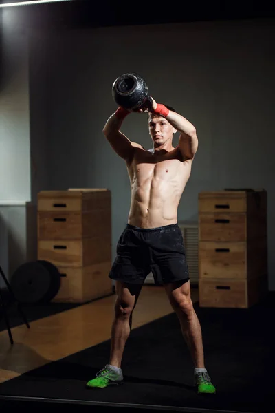 Treino cruzado intensivo. homem de sportswear trabalhando com kettle bell no ginásio — Fotografia de Stock