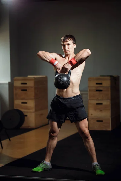 Treino cruzado intensivo. homem de sportswear trabalhando com kettle bell no ginásio — Fotografia de Stock