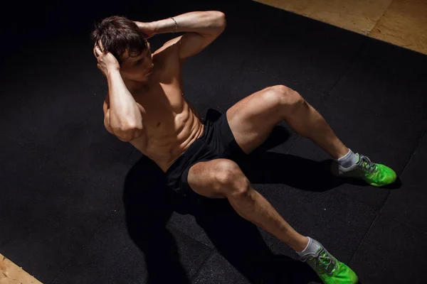 Muskularny mężczyzna wykonując robi siedzieć ćwiczeń. Sportowiec z sześciopak — Zdjęcie stockowe