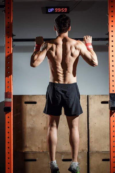 Aantrekkelijke jonge mannelijke volwassenen doen van pull ups op bar in cross fit training sportschool — Stockfoto